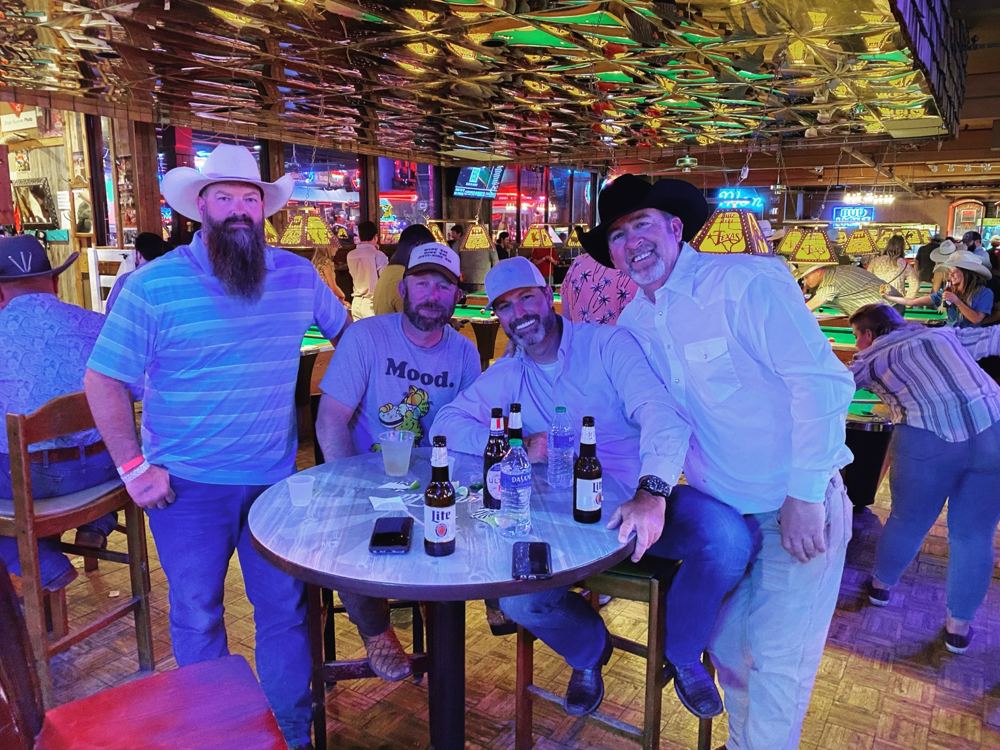 Group of four friends at a table wearing cowboy hats